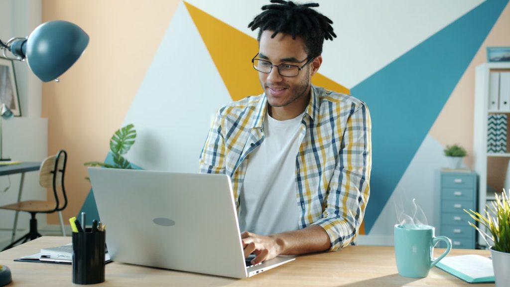 Man working on a laptop at a colorful desk.