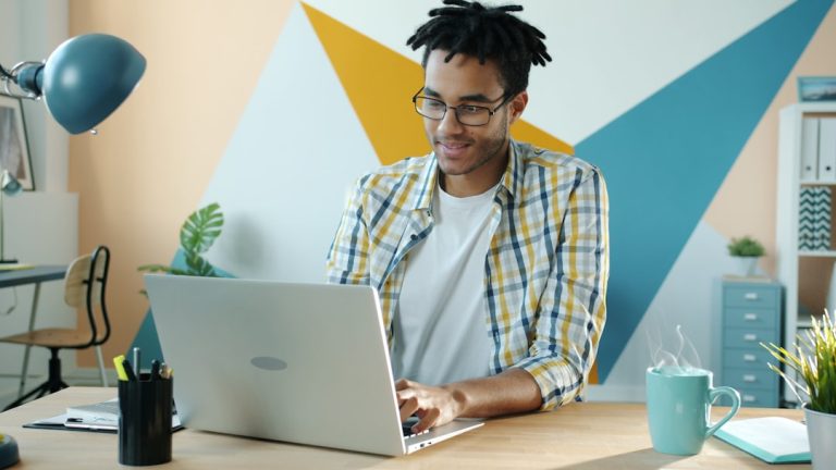 Man working on a laptop at a colorful desk.