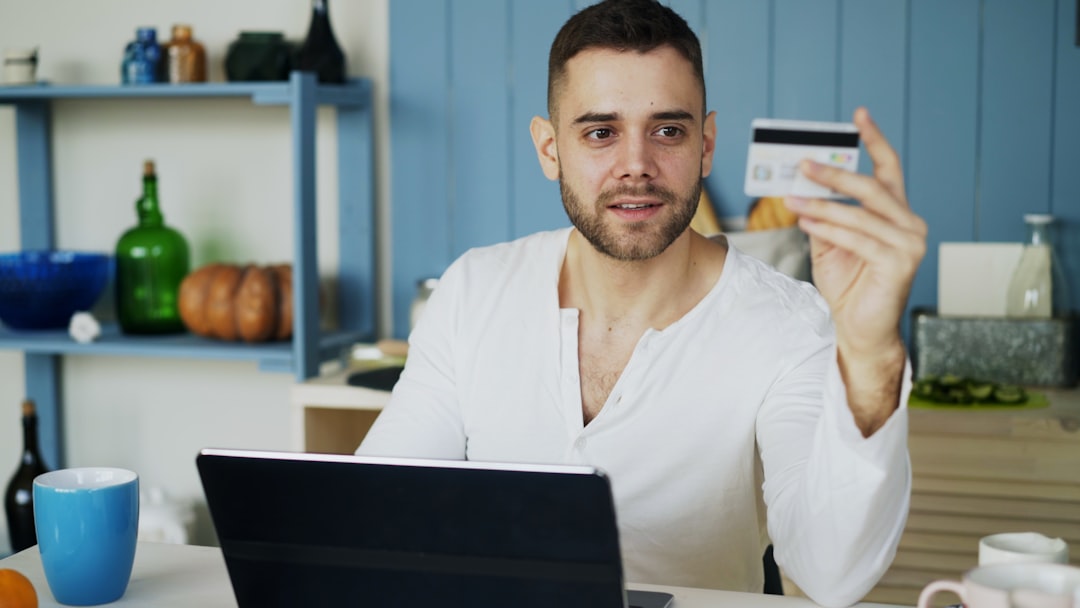 Man holding credit card while looking at laptop