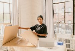 a woman standing next to a cardboard box on top of a table